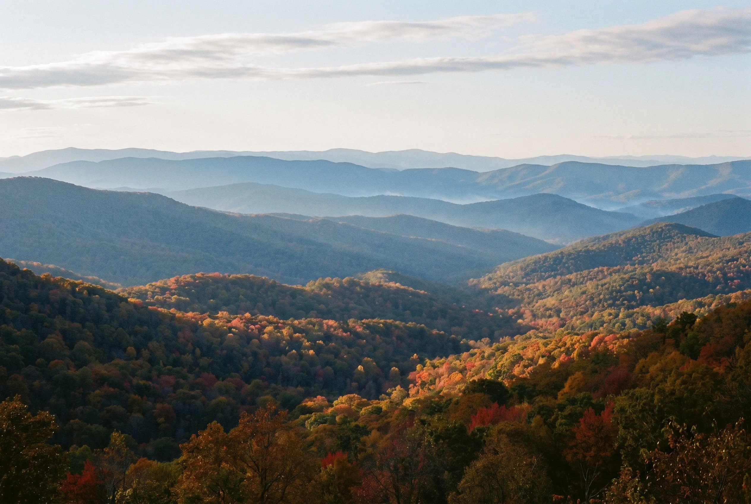 Layered blue mountain ridgelines under a hazy autumn sky.
